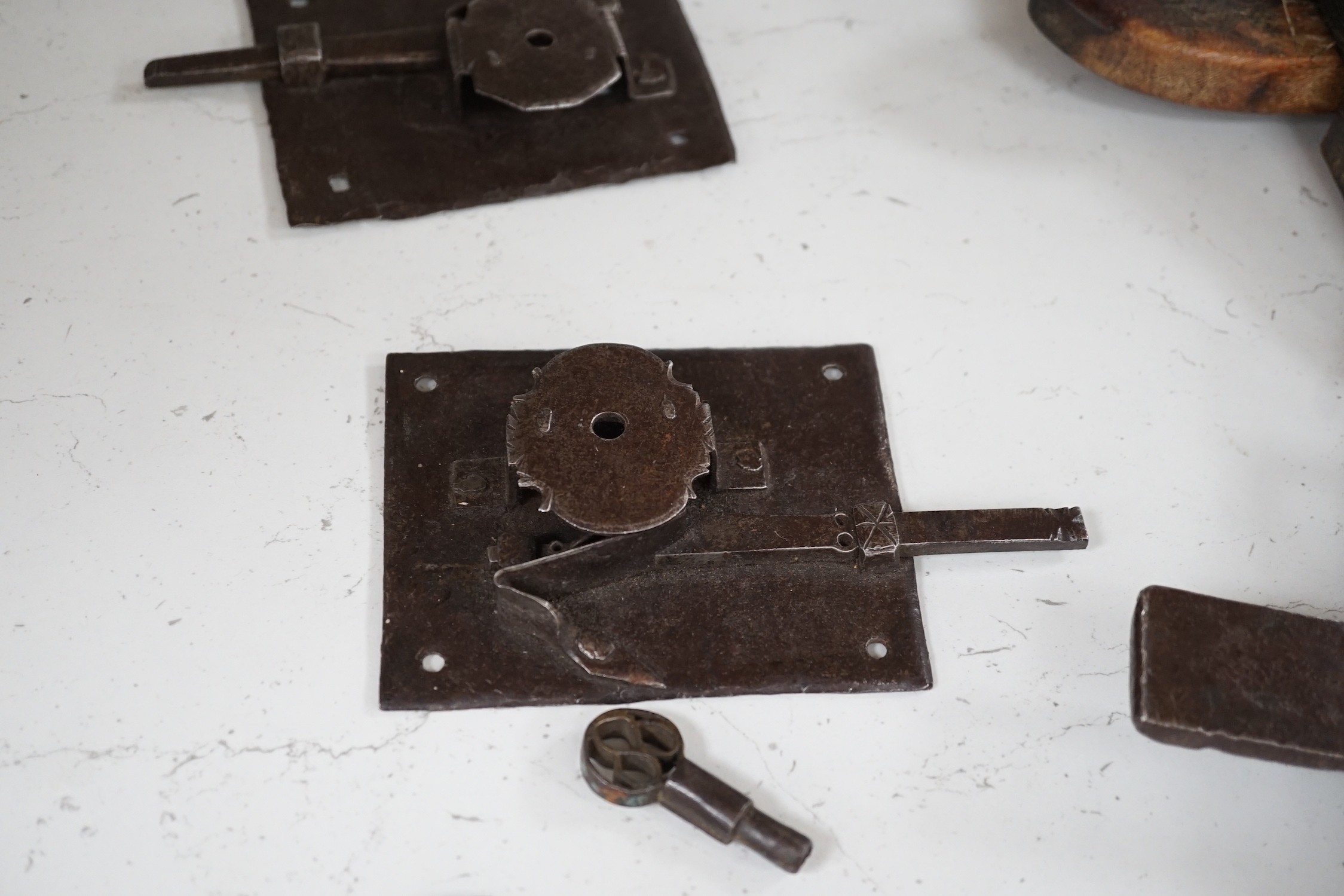 Three early ironwork lock plates with keys and a carved hardwood bolting lock